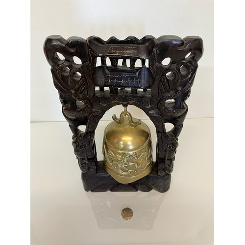 249 - Oriental temple bell, a cast bell decorated with dragons supported within a carved hard wood stand w... 