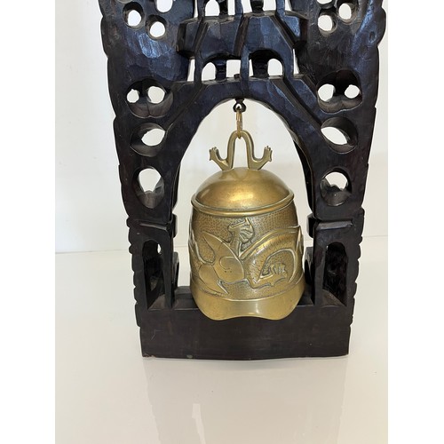 249 - Oriental temple bell, a cast bell decorated with dragons supported within a carved hard wood stand w... 