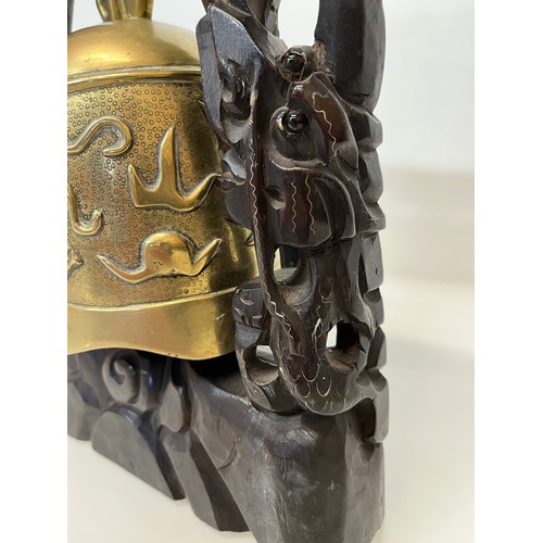 249 - Oriental temple bell, a cast bell decorated with dragons supported within a carved hard wood stand w... 