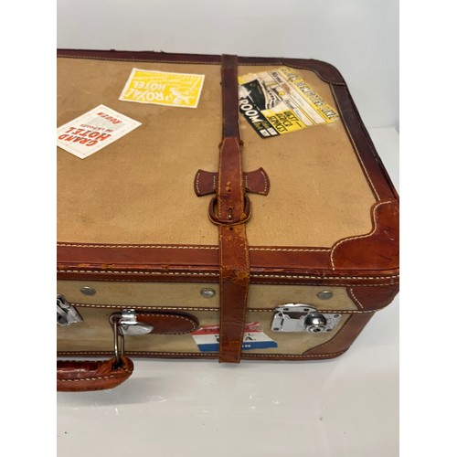 333 - Leather trimmed suitcase, with securing straps and a collection of baggage labels attached. 74 cm x ... 