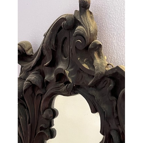 45 - A Black Forest hand carved wall mirror with two small shelves, 64 cm high x 34 cm wide.

This lot is... 