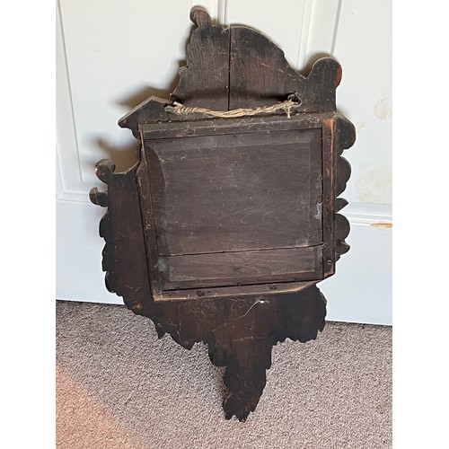 45 - A Black Forest hand carved wall mirror with two small shelves, 64 cm high x 34 cm wide.

This lot is... 