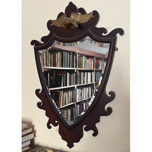 56 - Bevel edged shield shaped wall mirror surmounted with a carved and gilded eagle, 48 cm x 70 cm high.... 