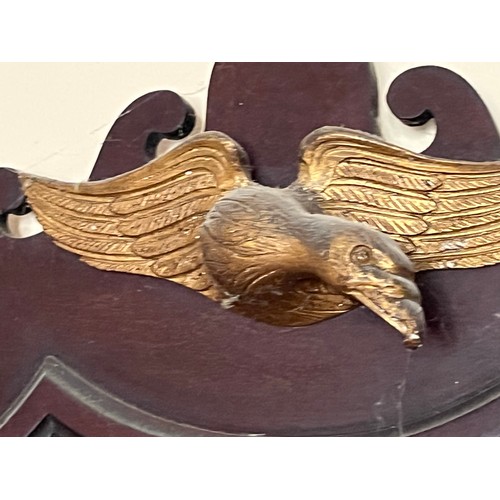 56 - Bevel edged shield shaped wall mirror surmounted with a carved and gilded eagle, 48 cm x 70 cm high.... 