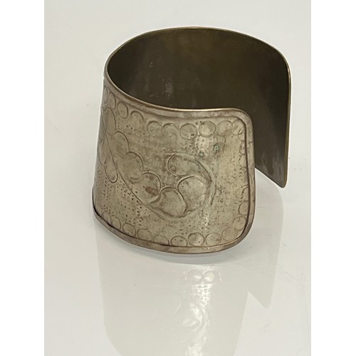 79 - Ethnic Jewellery, an embossed white metal wrist band decorated with botanical designs.

This lot is ... 