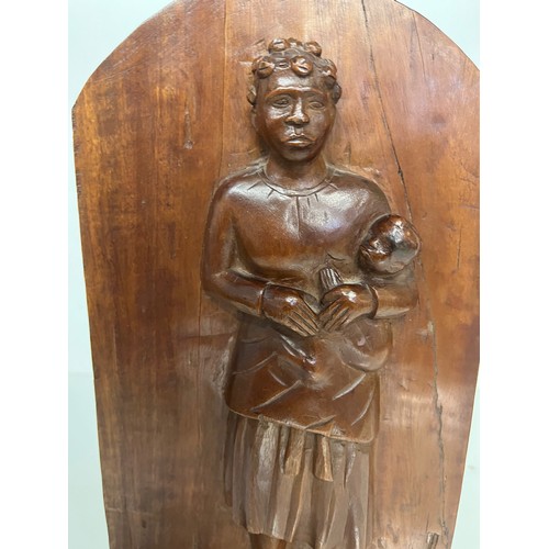 296 - A free standing hand carved wooden panel depicting a black mother holding a young child. 20 cm x 40 ... 