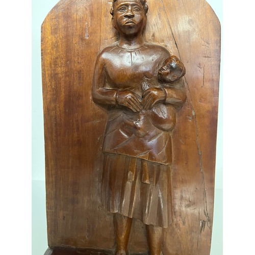 296 - A free standing hand carved wooden panel depicting a black mother holding a young child. 20 cm x 40 ... 