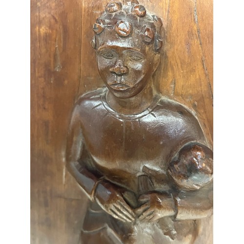 296 - A free standing hand carved wooden panel depicting a black mother holding a young child. 20 cm x 40 ... 