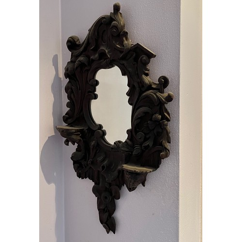 341 - A Black Forest hand carved wall mirror with two small shelves, 64 cm high x 34 cm wide.

This lot is... 