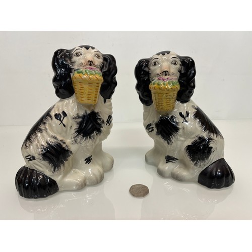 376 - A pair of Staffordshire wally dogs each holding a basket of flowers.

This lot is available for in-h... 