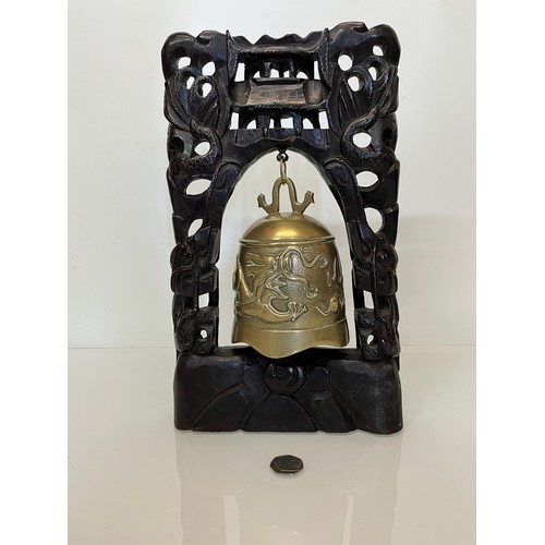 388 - Oriental temple bell, a cast bell decorated with dragons supported within a carved hard wood stand w... 