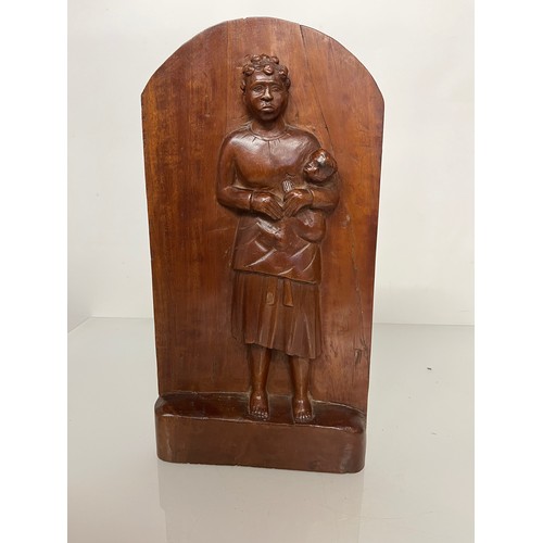 419 - A free standing hand carved wooden panel depicting a black mother holding a young child. 20 cm x 40 ... 