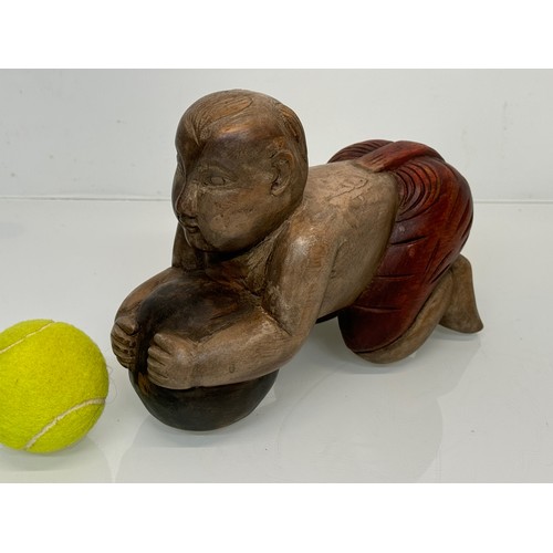 164 - Carved figure holding a ball. 26 cm long.

This lot is available for in-house shipping