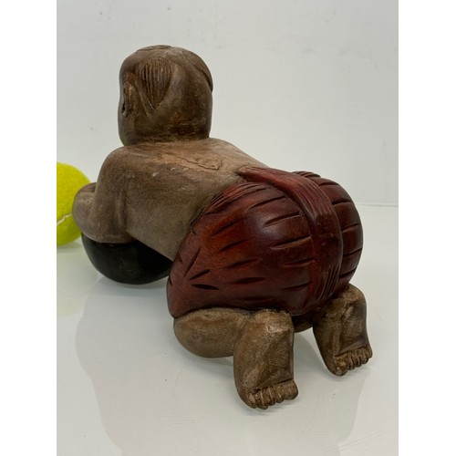 164 - Carved figure holding a ball. 26 cm long.

This lot is available for in-house shipping