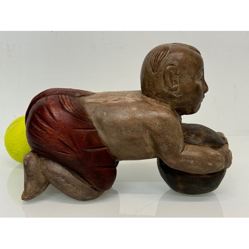 164 - Carved figure holding a ball. 26 cm long.

This lot is available for in-house shipping