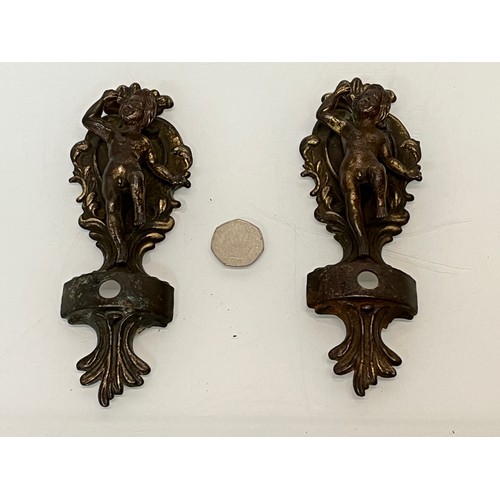 233 - A pair of cast furniture embellishments with cast in Cherub figures, each is 18 cm long.

This lot i... 