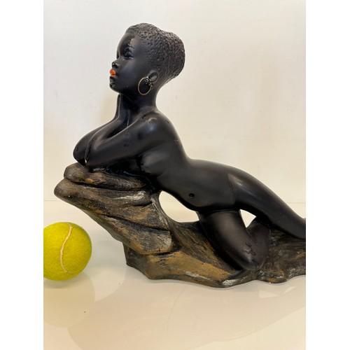 76 - Decorative figurine of a naked black female stretched out on a rock, 43 cm long.

This lot is availa... 