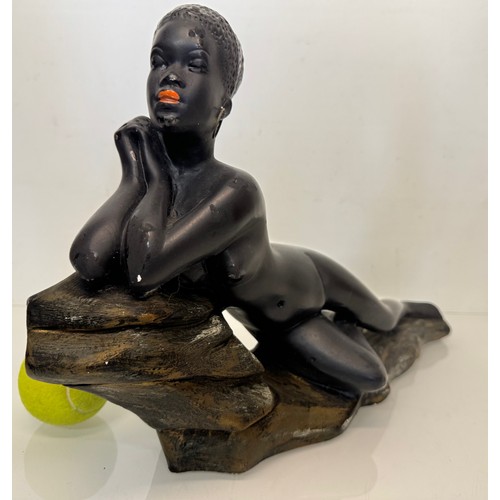 76 - Decorative figurine of a naked black female stretched out on a rock, 43 cm long.

This lot is availa... 