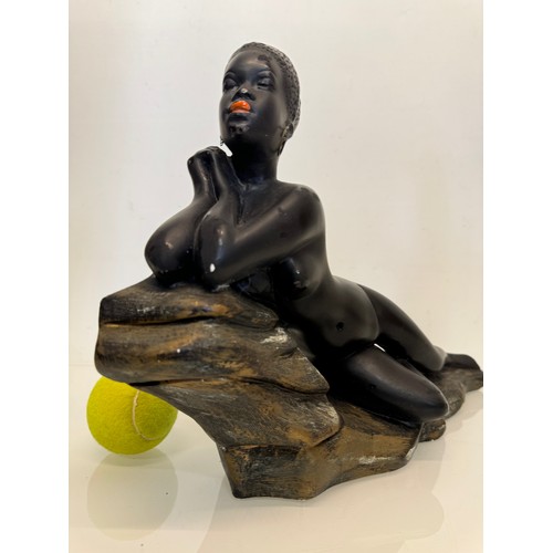 76 - Decorative figurine of a naked black female stretched out on a rock, 43 cm long.

This lot is availa... 