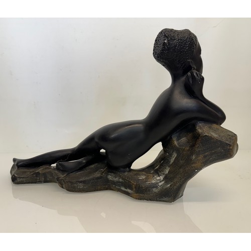 76 - Decorative figurine of a naked black female stretched out on a rock, 43 cm long.

This lot is availa... 