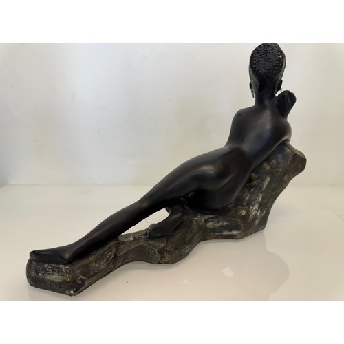 76 - Decorative figurine of a naked black female stretched out on a rock, 43 cm long.

This lot is availa... 