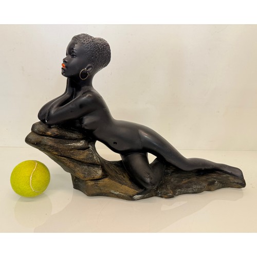 24 - Decorative figurine of a naked black female stretched out on a rock, 43 cm long.

This lot is availa... 