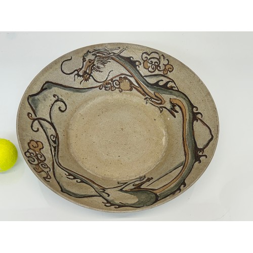 438 - Art pottery, a large stone ware bowl decorated with a dragon. 40 cm diameter x 10 cm high.

This lot... 