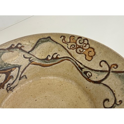 438 - Art pottery, a large stone ware bowl decorated with a dragon. 40 cm diameter x 10 cm high.

This lot... 