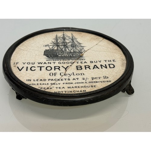 118 - Metal trivet with a ceramic heat stand to the centre advertising Victory Brand teas of Ceylon. 17 cm... 