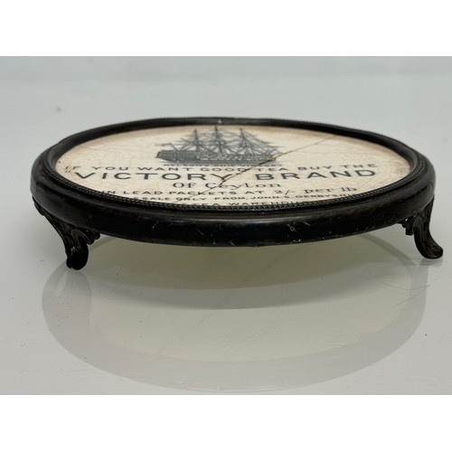 118 - Metal trivet with a ceramic heat stand to the centre advertising Victory Brand teas of Ceylon. 17 cm... 