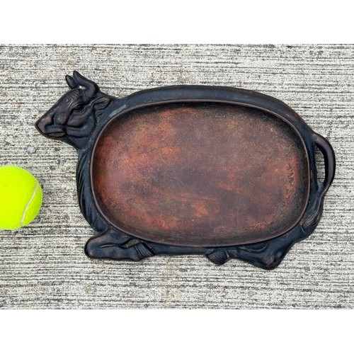 371 - Cast iron dish fitted within the centre of a seated cow form, 32 cm x 22cm 

This lot is available f... 