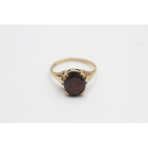 576 - 9ct gold oval garnet ornate shoulder solitaire ring (2g) SIZE- L