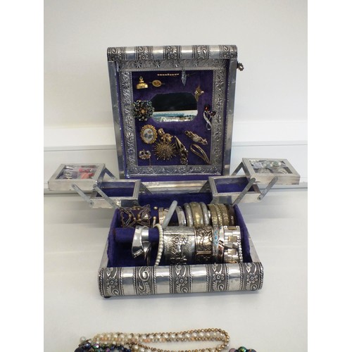 104 - LARGE SILVER COLOUR JEWELLERY BOX CRAMMED WITH BROOCHES, CLIP ON EARRINGS, BANGLES AND NECKLACES