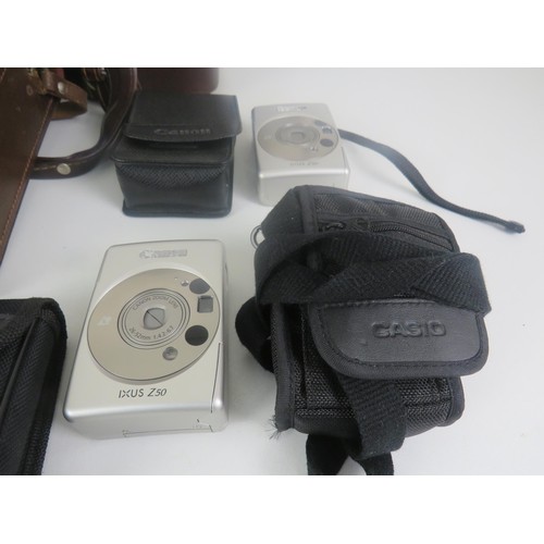 156 - CASIO, CANNON, OYLMPUS CAMERA IN CASE INCLUDING COMPARTMENT OF VARIOUS FILMS AND VIVITAR BINOCULARS