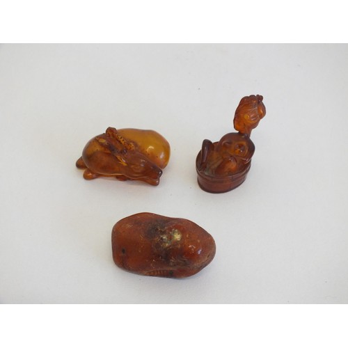 274 - 2 AMBER NETSUKES INCLUDES JAPANESE LADY IN A BATH TUB (AS FOUND) and A PIECE OF NATURAL RAW AMBER AP... 