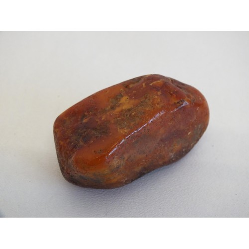 274 - 2 AMBER NETSUKES INCLUDES JAPANESE LADY IN A BATH TUB (AS FOUND) and A PIECE OF NATURAL RAW AMBER AP... 