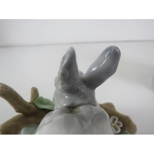 92 - TWO LLADRO FIGURES- GIRL SITTING ON CHAIR WITH VASE OF FLOWERS AND RABBIT EATING LEAVES