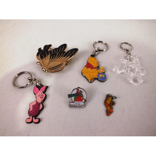 37 - Four Disney keyrings, Disney badge and a black & gold butterfly brooch.