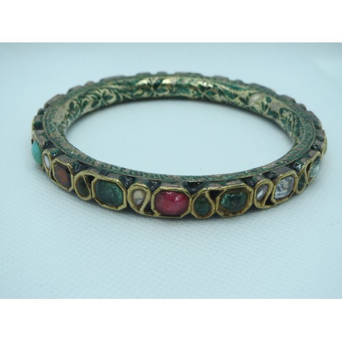 86 - An Indian enamelled and gem-set gold colour bangle includes coral, turquoise and garnet with green e... 