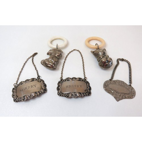 74 - Two vintage white metal baby teething rattles and three silver plated decanter labels.