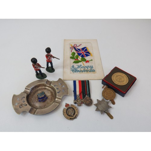 213 - Militaria collection to include miniature medal, postcard, regiment ashtray, cap badges coin and sol... 