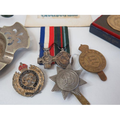 213 - Militaria collection to include miniature medal, postcard, regiment ashtray, cap badges coin and sol... 