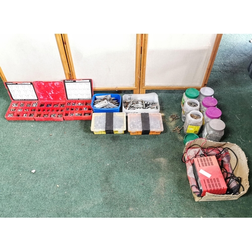 13 - Large quantity of screws in containers plus a car  battery charger drill bits etc