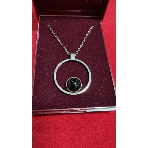 153 - White metal pendant and 16 inch chain with a black stone marked GEM