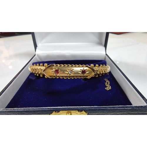 310 - Vintage hallmarked 9ct yellow gold oval hinge bangle, with ornate design inset with 2 genuine Ruby s... 