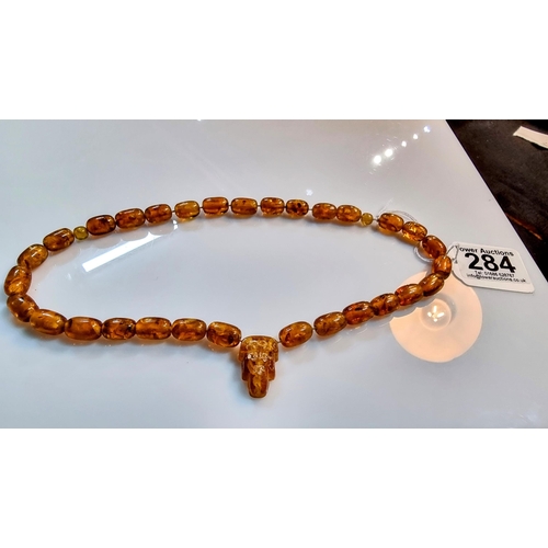 284 - Unusual vintage genuine baltic amber beaded necklace with inclusions with a face, skull carved penda... 