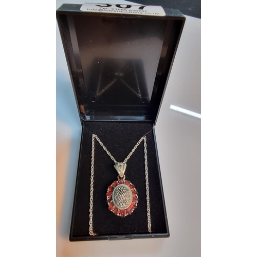 307 - 925 Silver ornate pendant with striking design inset with Marcasite stones surrounded by garnet ston... 