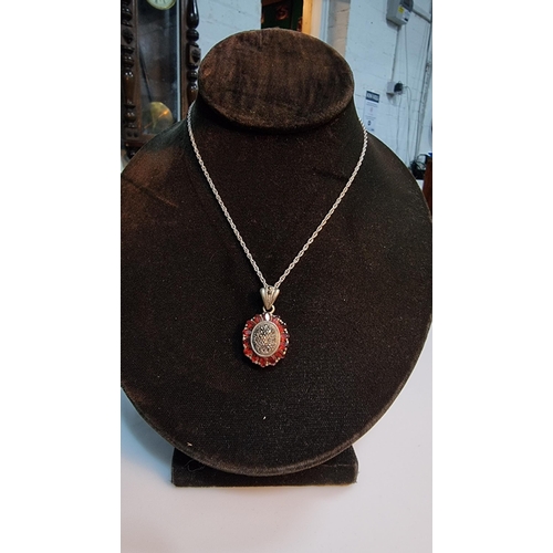 307 - 925 Silver ornate pendant with striking design inset with Marcasite stones surrounded by garnet ston... 