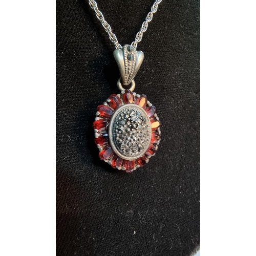 307 - 925 Silver ornate pendant with striking design inset with Marcasite stones surrounded by garnet ston... 