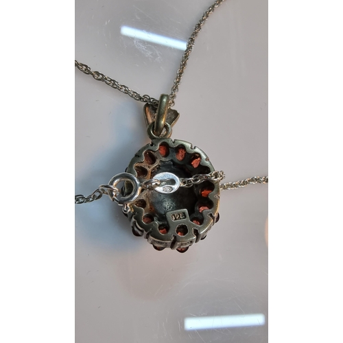 307 - 925 Silver ornate pendant with striking design inset with Marcasite stones surrounded by garnet ston... 